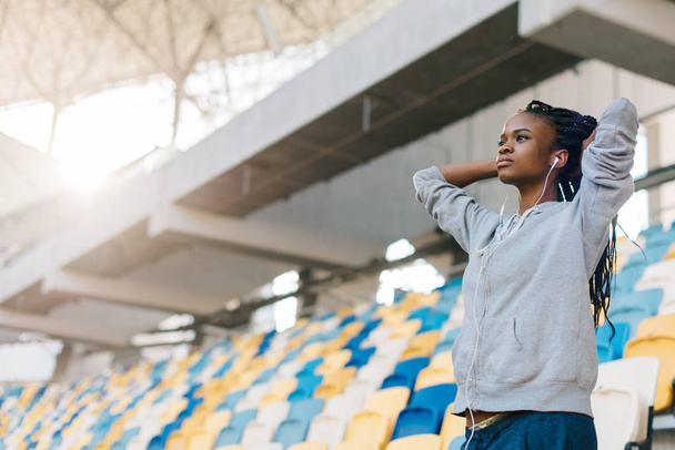 Close-up portrait of the concentrated afro-american teenager watching the match on the stadium. - 写真・画像