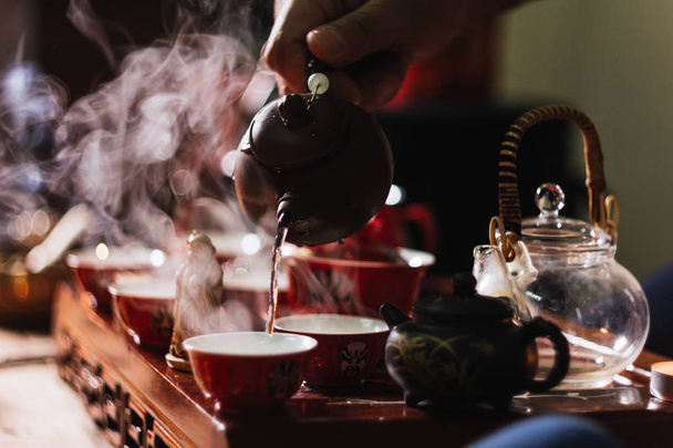 Tea ceremony. The man pours hot water from the teapot into the red chinese tea cup - Fotografie, Obrázek