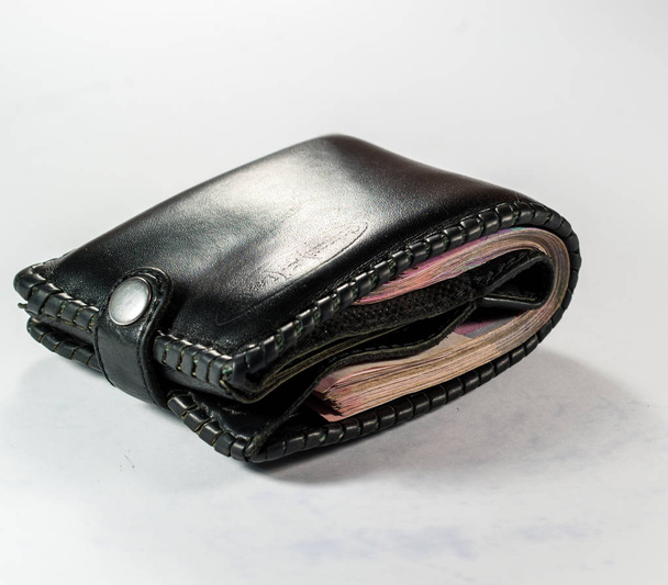 Monedero negro lleno de dinero apretado
 - Foto, imagen