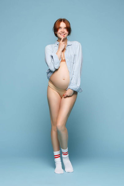 Young beautiful pregnant woman standing on blue background - Φωτογραφία, εικόνα