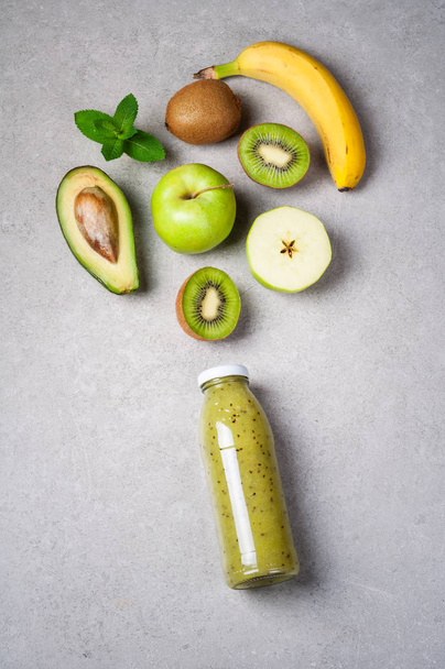 gesunder grüner Smoothie in Flasche und Zutaten. gesunde Ernährung, Superfoods, Entgiftung, Ernährung. Kiwi, Apfel, Spinat, Avocado, Banane und Minze. Vegetarisches Essen - Foto, Bild