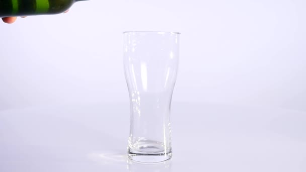A bottle of beer is poured into a cup on a white background - Filmati, video