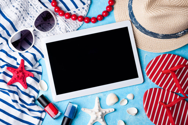 Accessori donna estivi: occhiali da sole, cappello, infradito, gioielli, camicia e tablet su sfondo blu. Spiaggia, vacanze, viaggi e freelance
 - Foto, immagini