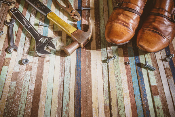 zapatos de cuero grunge y muchas herramientas de variedad sobre fondo de madera
 - Foto, Imagen