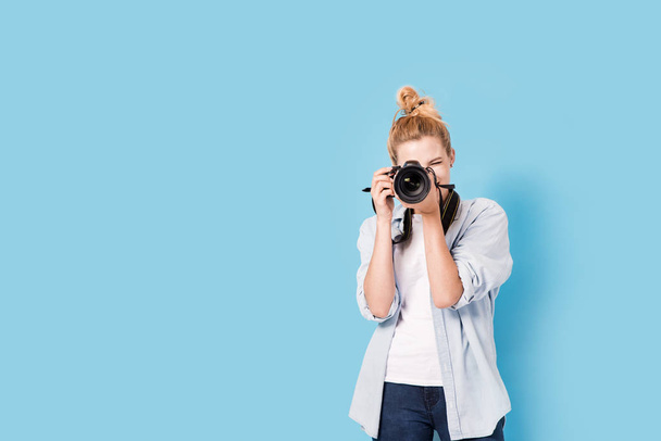 Young blonde photographer is taking a photo. Model isolated on a - Foto, afbeelding