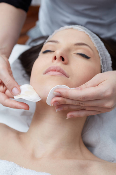  Relaxing beautiful woman having a massage for her skin on a face in beauty salon - Fotó, kép