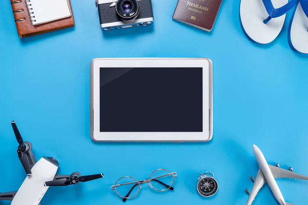 Pantalla tablet negra rodeada de accesorios de viaje
 - Foto, Imagen
