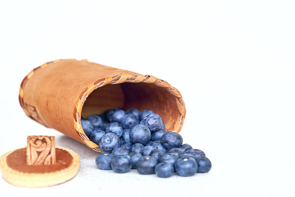 Blueberries near bark basket on a white background - Photo, Image