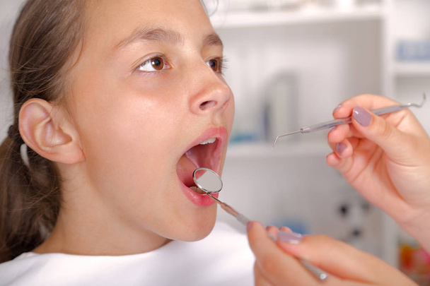 Close-up of little girl opening his mouth wide during treating h - Foto, imagen