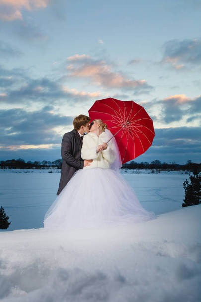 Bride and groom with big red umbrella - Valokuva, kuva
