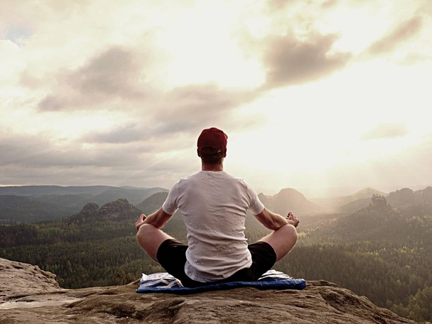 Yoga pratiquant au sommet de la montagne avec vue aérienne sur la vallée de montagne. Grand sportif pratiquant le yoga
 - Photo, image