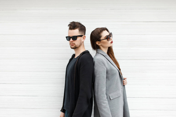 Handsome guy and beautiful girl in stylish clothes posing near white wooden wall - Photo, Image