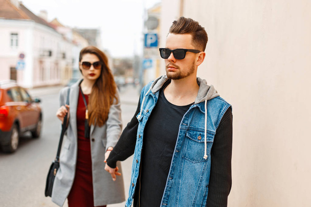 Красива стильна молода пара з сонцезахисними окулярами в модному одязі, що йде по місту. Руки коханців
. - Фото, зображення