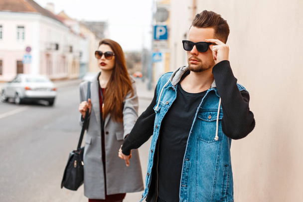 Young beautiful couple in sunglasses goes on the street - Φωτογραφία, εικόνα