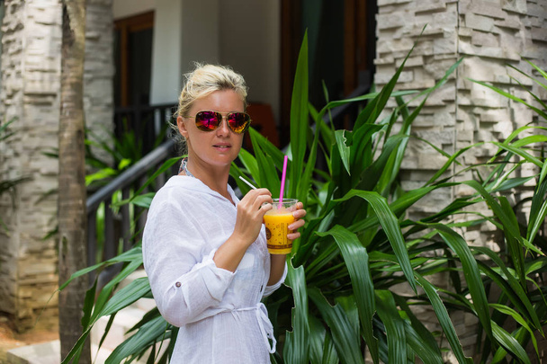 Donna che tiene un cocktail di frutta su una spiaggia tropicale
 - Foto, immagini