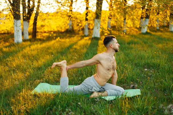 Mann praktiziert Yoga in einem Park bei schönem Sonnenuntergang. Gesunder Lebensstil - Foto, Bild