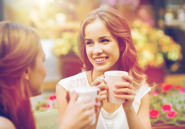 smiling young women with coffee cups at cafe - Fotoğraf, Görsel