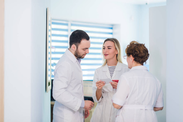 Mature doctor discussing with nurses in a hallway hospital. Doctor discussing patient case status with his medical staff after operation. - Foto, Imagen