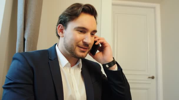 Side view of portrait of caucasian young business man in suit and shirt talking with business partner on mobile phone in the office. - Séquence, vidéo