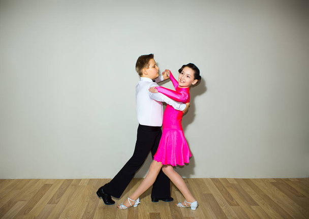 El niño y la niña posando en el estudio de baile en gris. El concepto de baile de salón
 - Foto, imagen