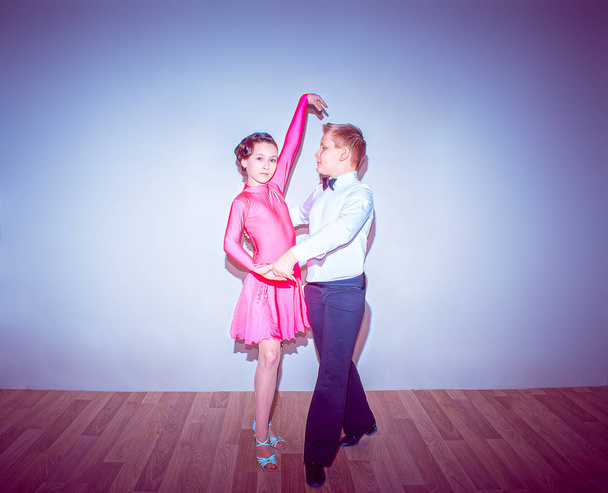 De jongen of het meisje die zich voordeed op dansstudio op blauw in tango houding. Het concept van stijldansen - Foto, afbeelding