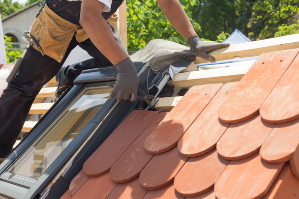 Kädet katontekijä tehdyn laatta katolla. Asentaminen luonnollinen punainen laatta käyttäen pihdit. Katto mansardi ikkunat
 - Valokuva, kuva