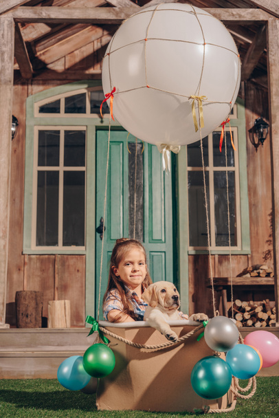 girl with puppy in air balloon box - Фото, изображение