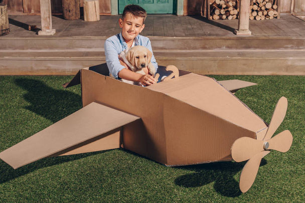 boy with puppy in cardboard airplane - Photo, Image
