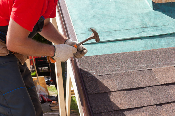 Roofer constructor trabajador utilizar un martillo para la instalación de tejas para techos
. - Foto, Imagen