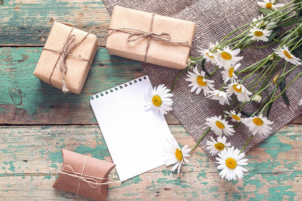 Bouquet of daisies with gift boxes and empty note pad for messag - Fotoğraf, Görsel