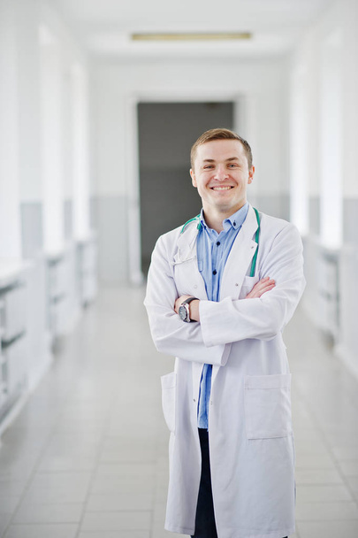 Красивий і впевнений молодий лікар у білому пальто зі стетоскопом
 - Фото, зображення