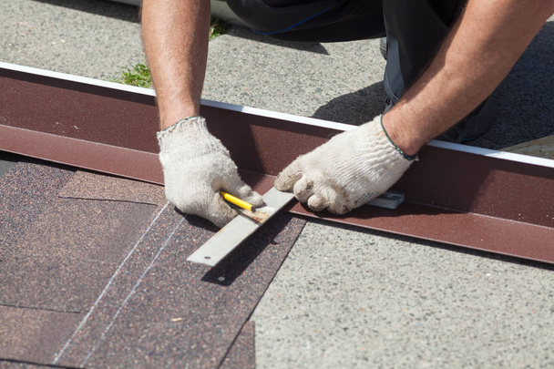 Instalación de tejas naturales. Roofer constructor trabajador marca la distancia entre las costuras
. - Foto, imagen