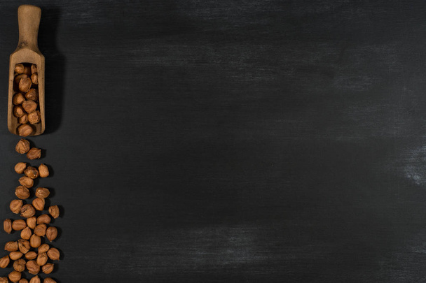 Hazelnuts in a wooden scoop on a black chalkboard.  - Fotoğraf, Görsel
