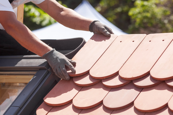 Manos de tejado colocando baldosas en el techo. Instalación de azulejos rojos naturales
 - Foto, Imagen