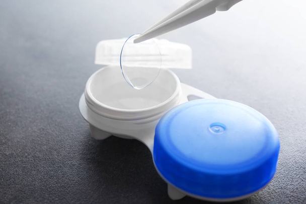 Tweezers with contact lens and plastic container  - Foto, afbeelding