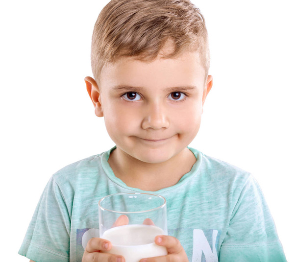 Adorable little boy in blue T-shirt with a glass full of fresh milk, isolated on a white background. Handsome baby boy is holding milk or kefir, isolated on white background.  A cute boy with milk.  - Fotó, kép