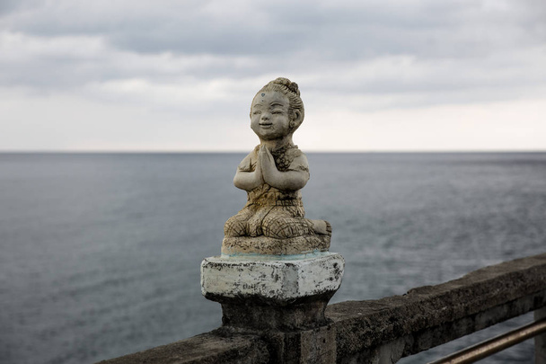 Stenen sculpturen van boeddhistische monniken met zee achtergrond - Foto, afbeelding