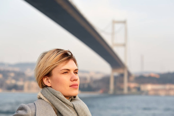 Portrait of a young woman under the Bosporus bridge. - Photo, Image