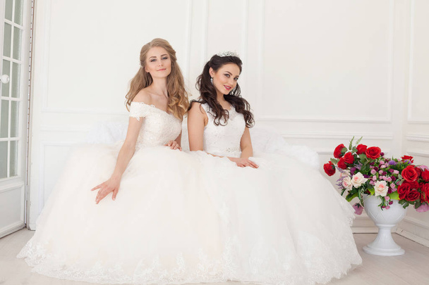 Portrét dvou mladých žen v svatební šaty v bílé hale - Fotografie, Obrázek