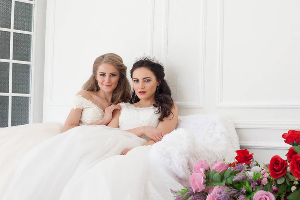 Portrait of two young women in wedding dresses in White Hall - Photo, Image
