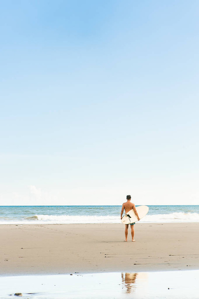 Handsome man with surfing board on spot. - 写真・画像