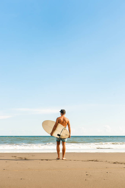 Handsome man with surfing board on spot. - Фото, изображение
