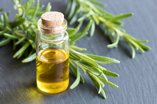 A bottle of essential oil with fresh rosemary twigs - Foto, afbeelding