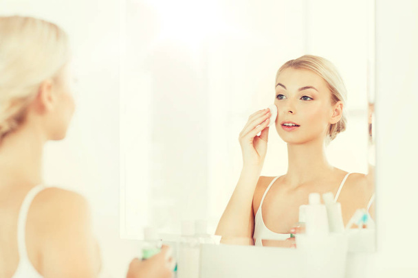 молода жінка з лосьйоном миття обличчя у ванній
 - Фото, зображення