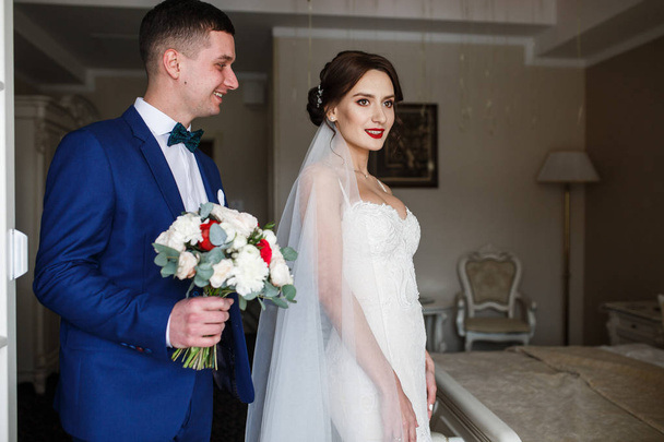 Groom stands behind bride with wedding bouquet  - 写真・画像