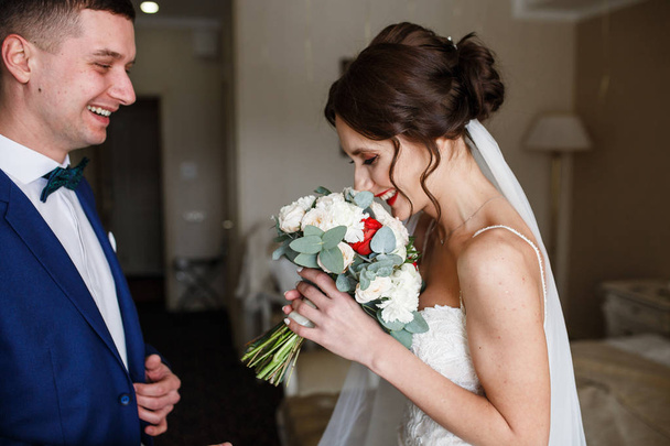 Groom stands behind bride with wedding bouquet  - Фото, изображение