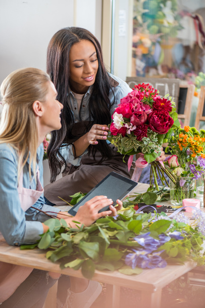 мультиэтнические флористы с цифровыми планшетами и цветами
 - Фото, изображение