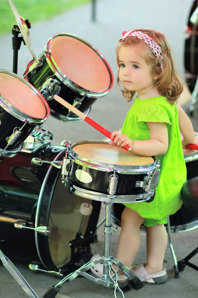 Chica de un año en verde romperse aprendiendo a tocar la batería
 - Foto, imagen