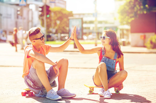 teenage couple with skateboards on city street - Фото, изображение