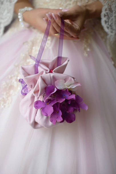 紫の花の詳細を持つミニ結婚式バッグを持って花嫁のクローズ アップ - 写真・画像